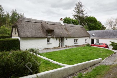 Exteriors of thatched cottage with garden