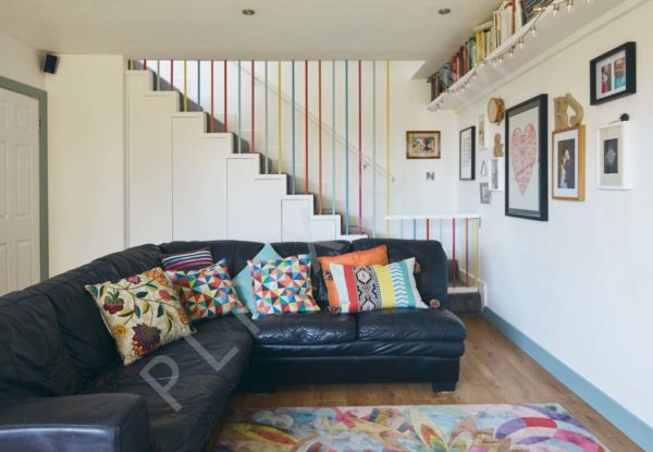 Open plan living room timber flooring rug shelving stairs storage artwork balustrade